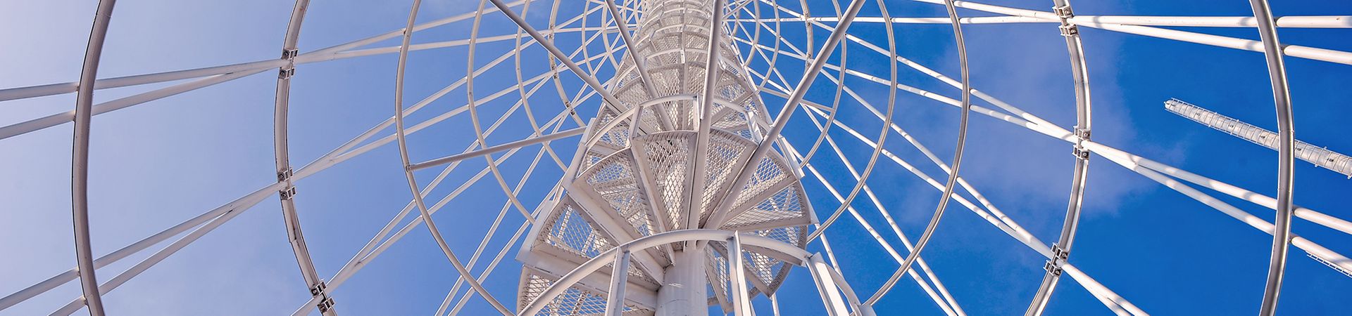 Telephone communication tower with spiral staircase photographed against the blue sky.