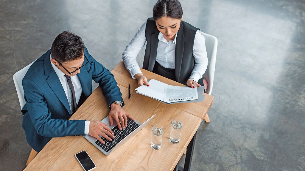 high angle view of young asian business people working with laptop and contract in office
